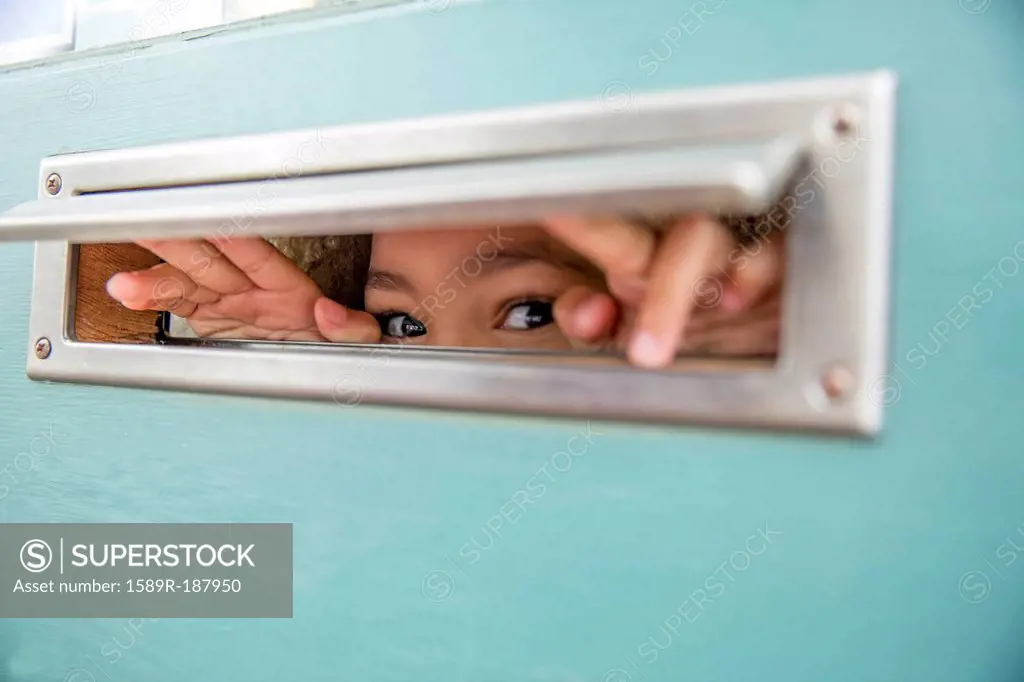 Mixed race girl peeking through mail slot