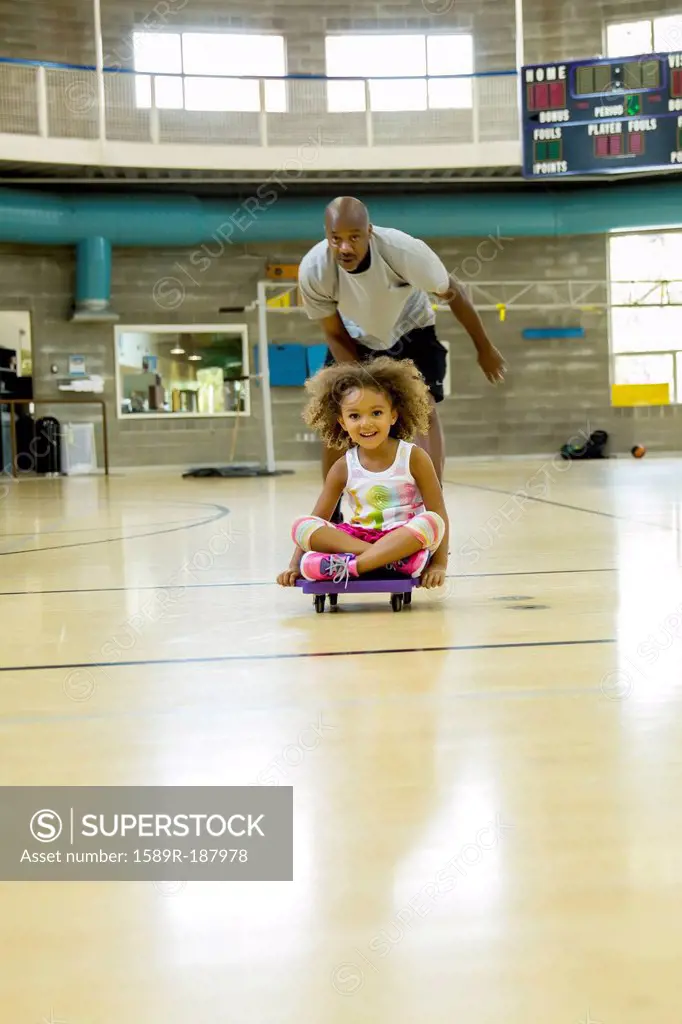 Father and daughter playing on basketball court