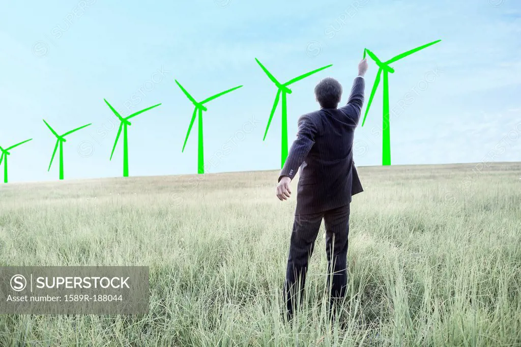 Indian businessman drawing wind turbines on sky