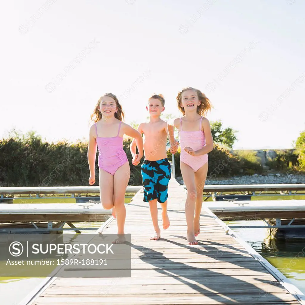 Caucasian children running on dock