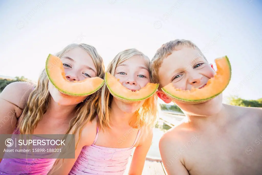 Caucasian children eating cantaloupe slices
