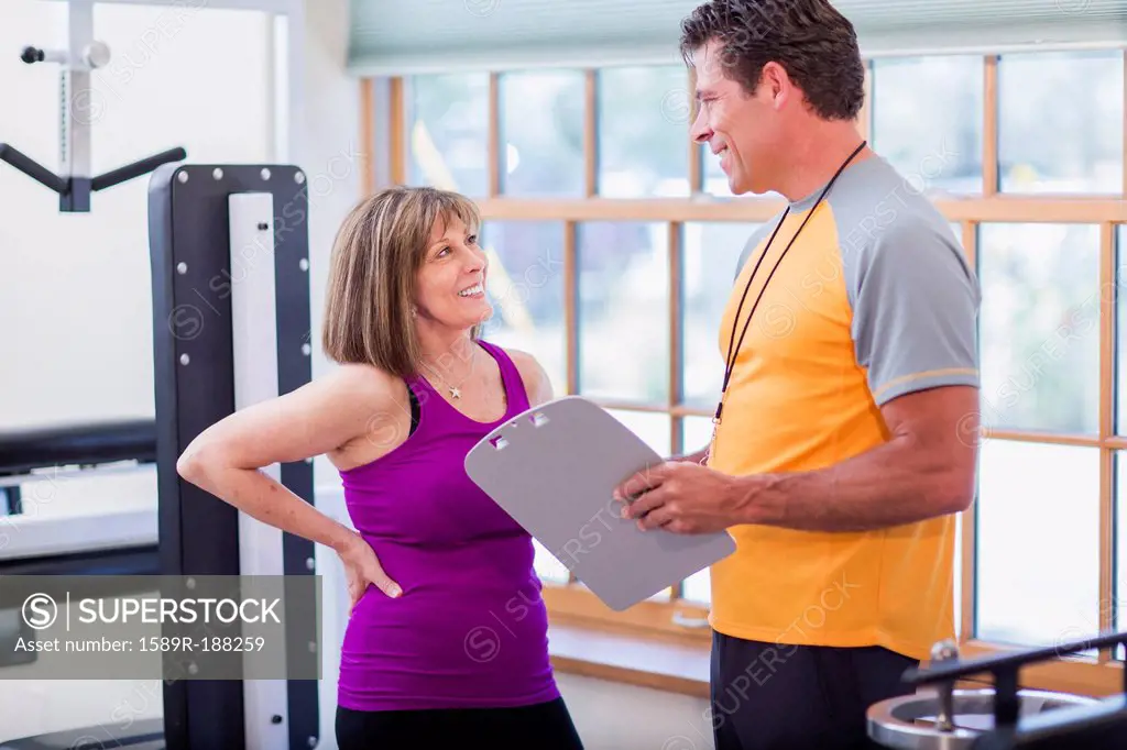 Caucasian woman working with personal trainer in gym