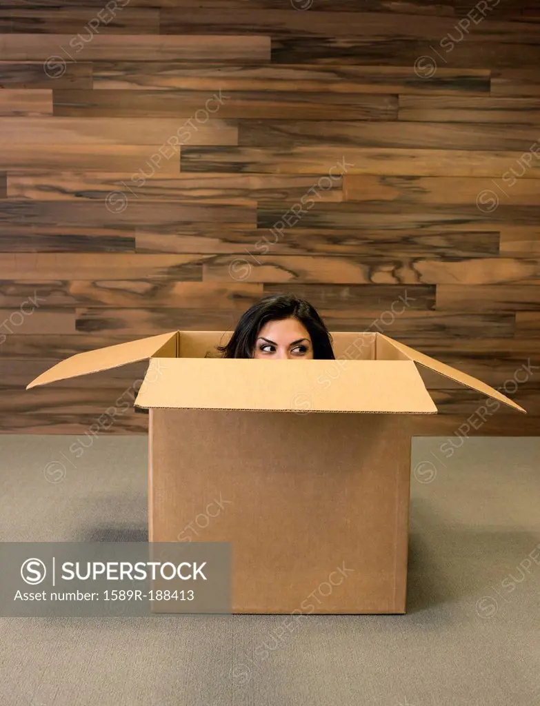 Mixed race woman hiding in cardboard box