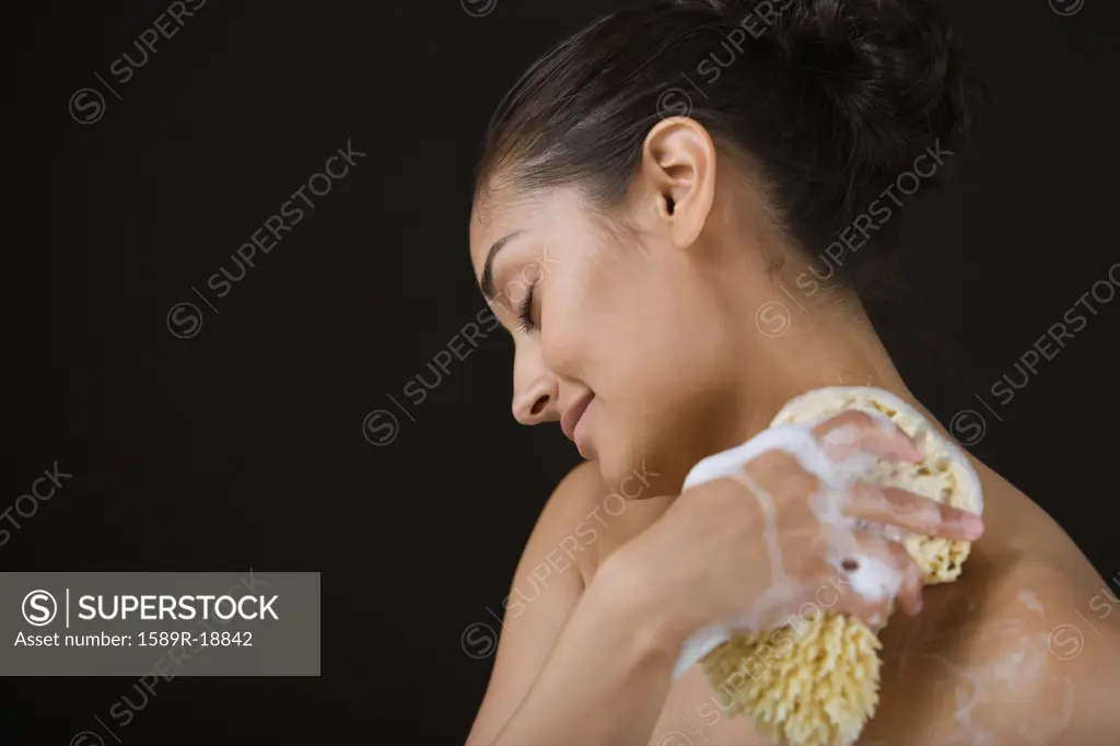 Close up profile of woman bathing with sponge
