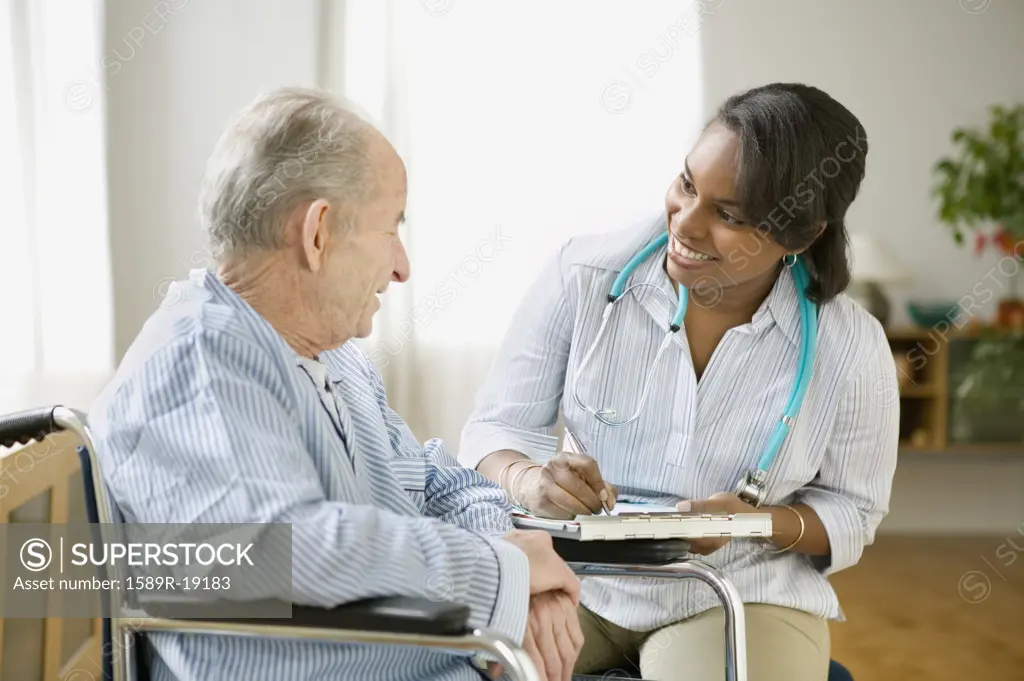 Nurse recording elderly man's condition