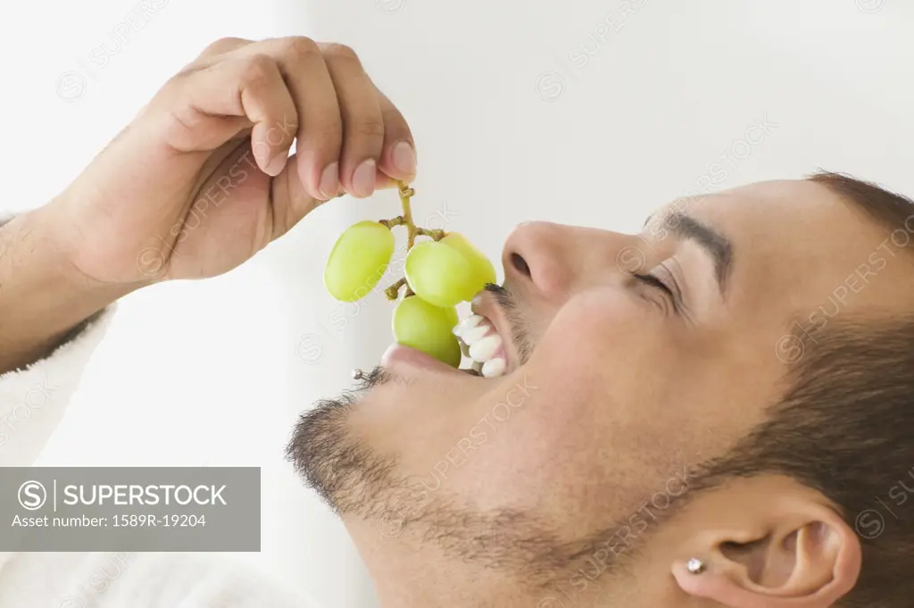 Young man eating grapes