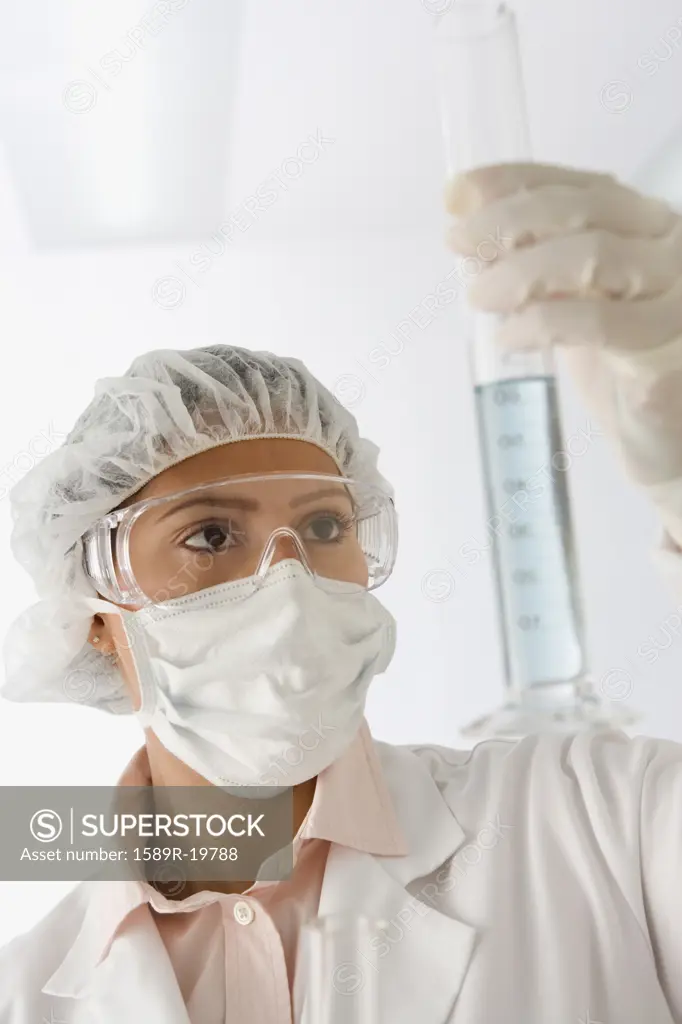 Female scientist examining graduated cylinder