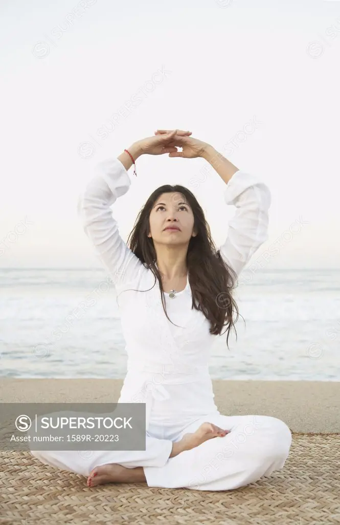 Young woman practising yoga on the beach