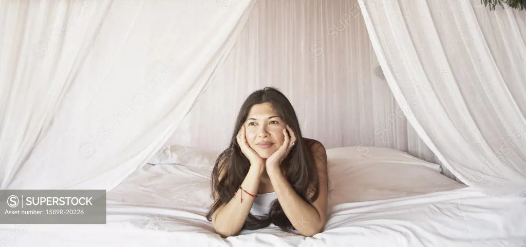 Young woman relaxing in a four-poster bed