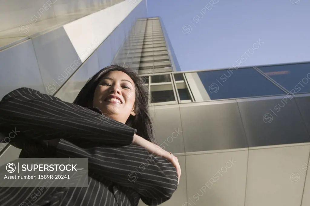 Low angle view of businesswoman smiling in front of highrise