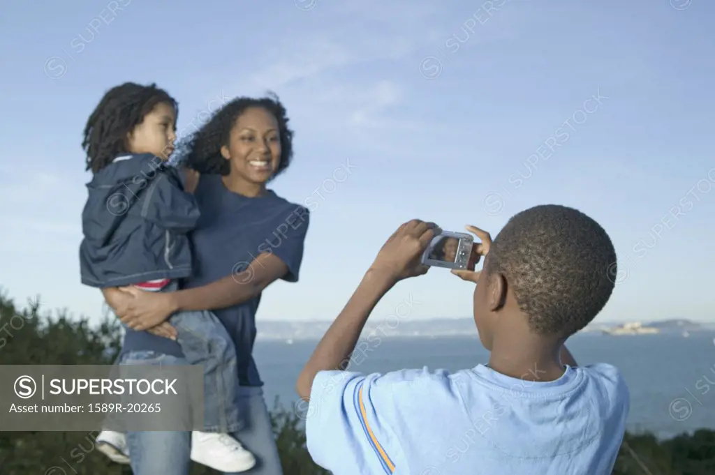 Young boy taking a picture of his mother and sister