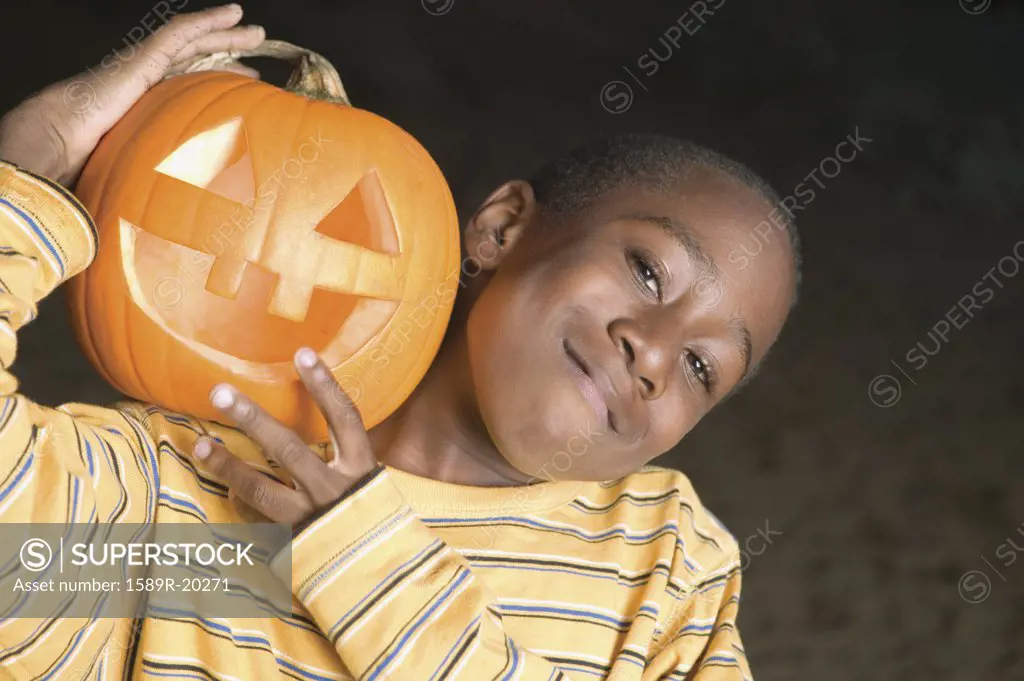 Young boy smiling for the camera with a jack o lantern