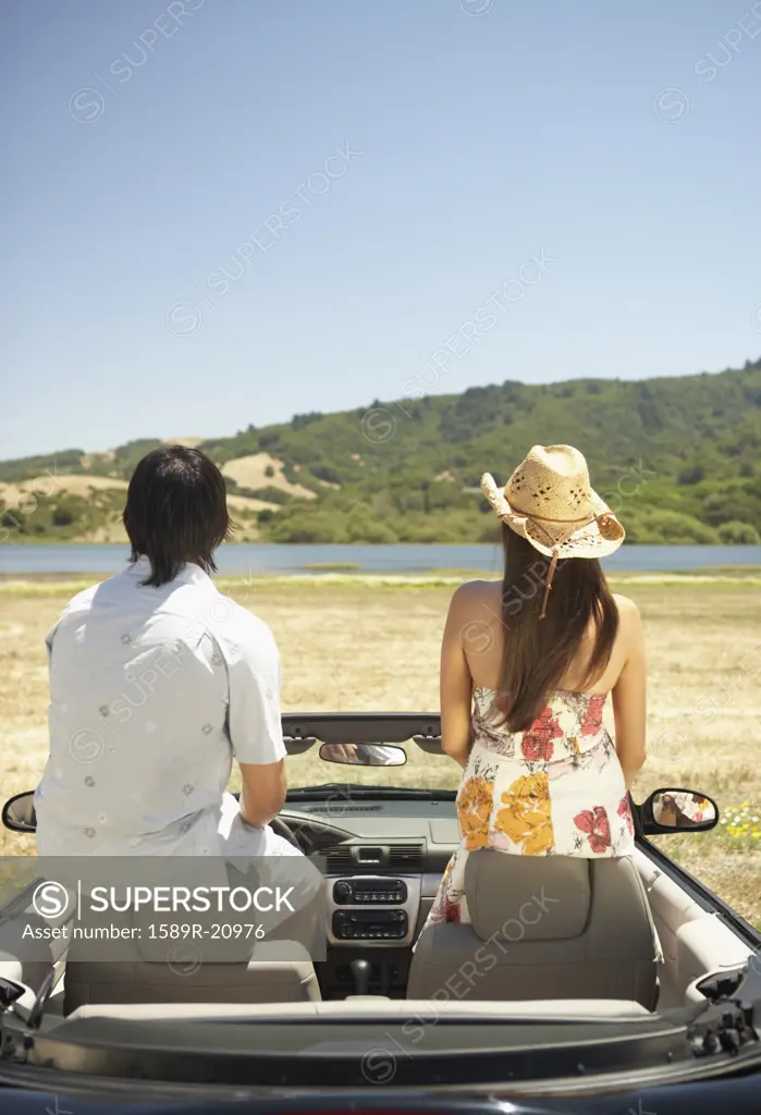 Couple sitting on headrests inside a convertible