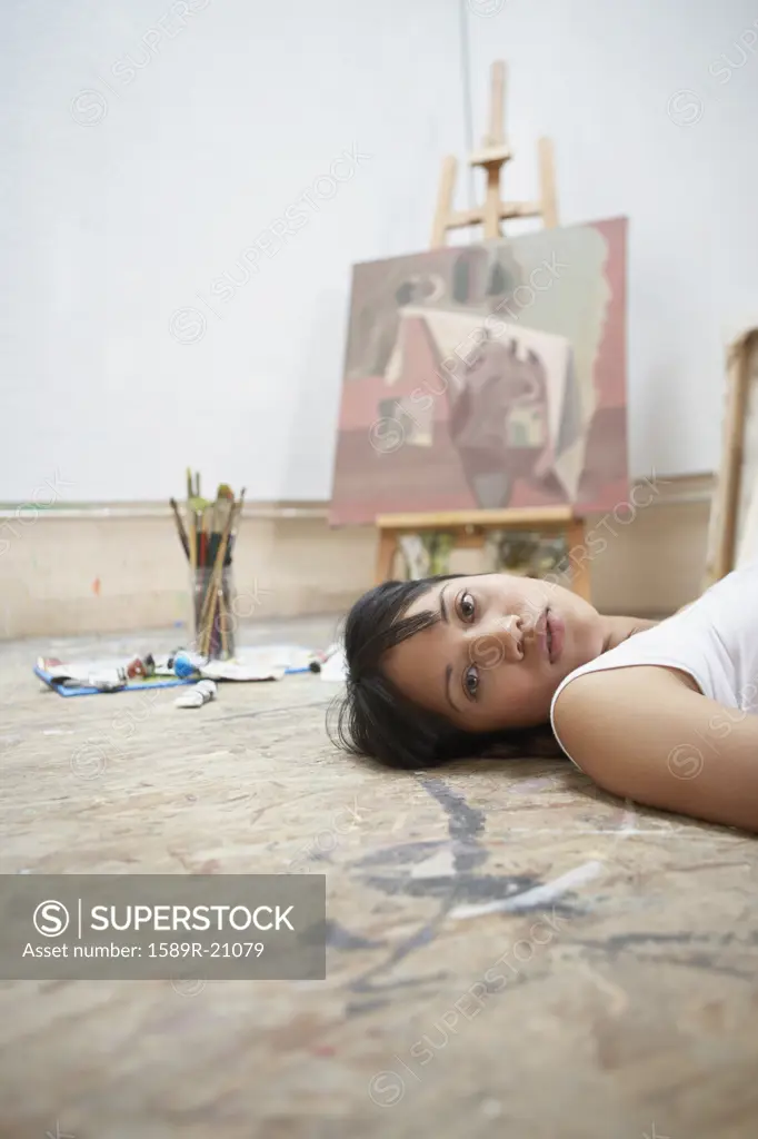 Young woman lying on the floor by a painting