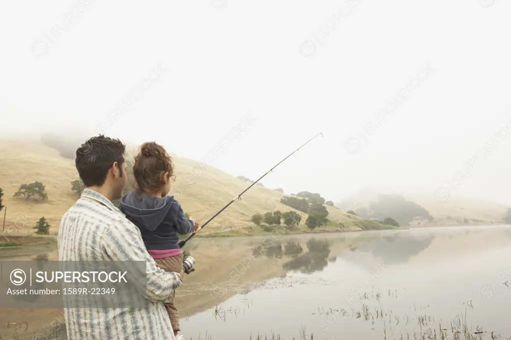 Father and daughter fishing off a pier