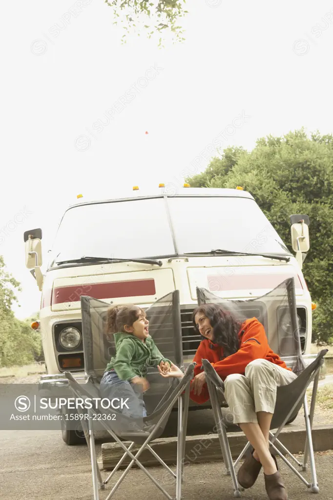 Mother and daughter sitting by truck outdoors