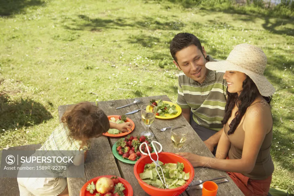 Family eating on a picnic table outdoors