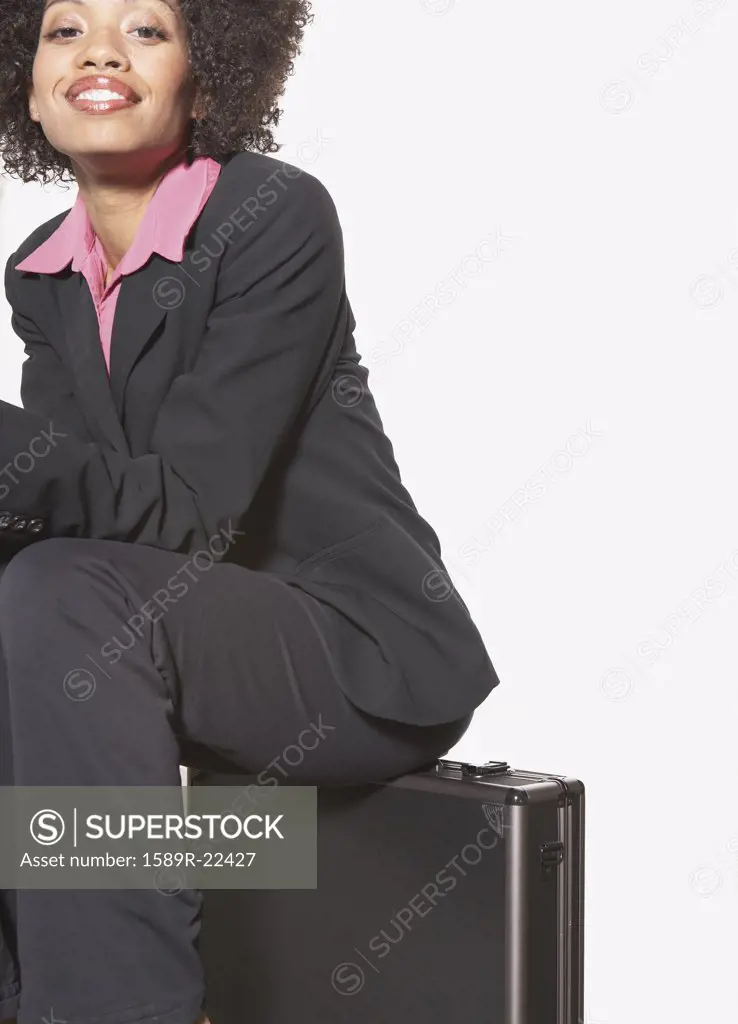 Businesswoman sitting on metal briefcase