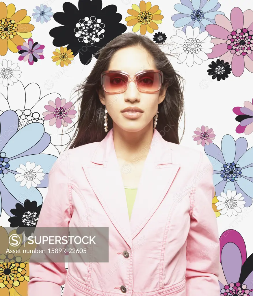 Woman posing for the camera in sunglasses against floral background