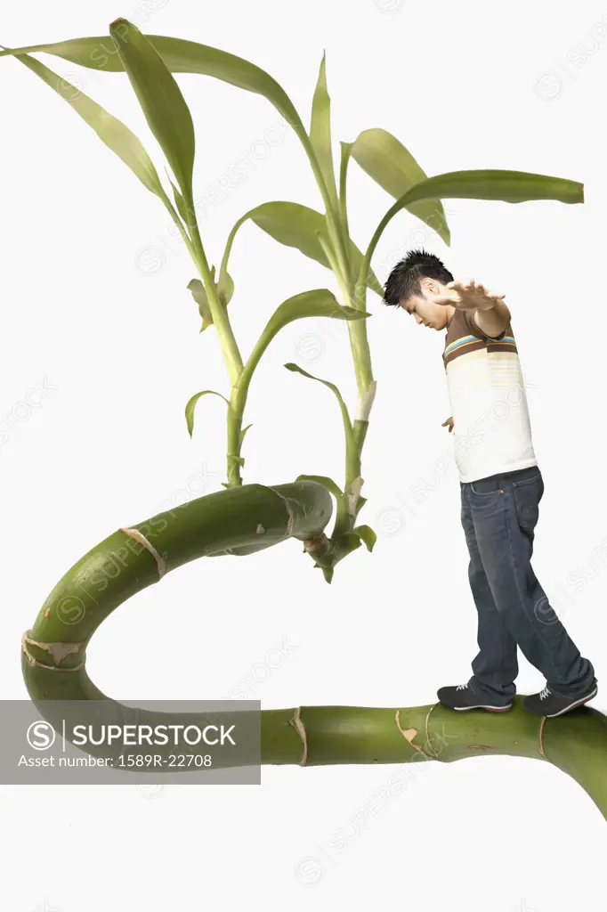 Young man balancing on a giant plant