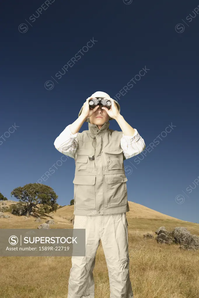 Explorer using binoculars in grassy area