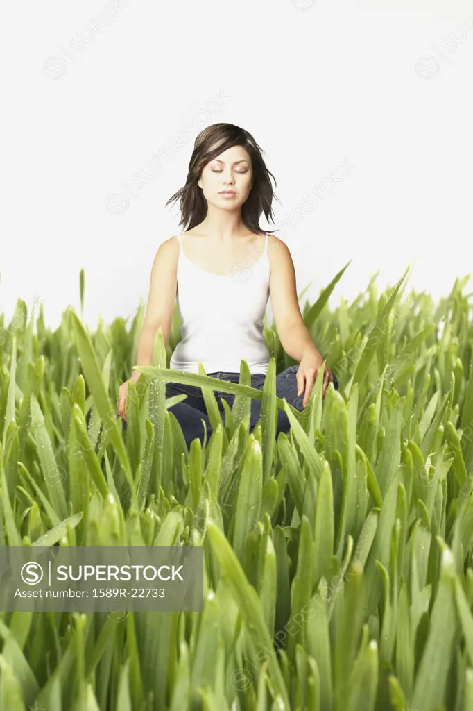 Young woman meditating in tall grass