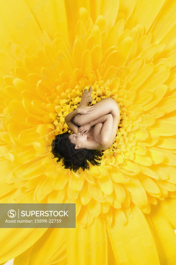 Young nude woman curled up in a giant flower