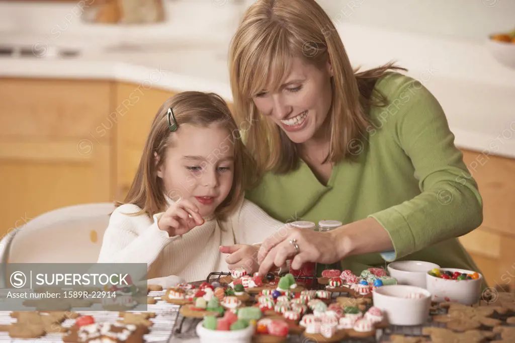 Mother and daughter decorating homemade gingerbread cookies, Richmond, Virginia, United States