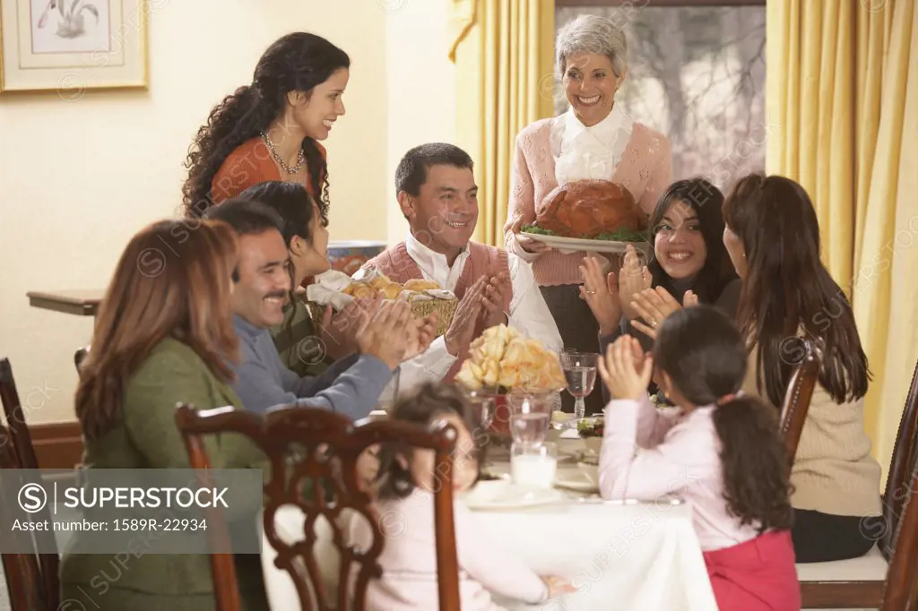 Hispanic grandmother presenting turkey to her family at the dinner table, Richmond, Virginia, United States