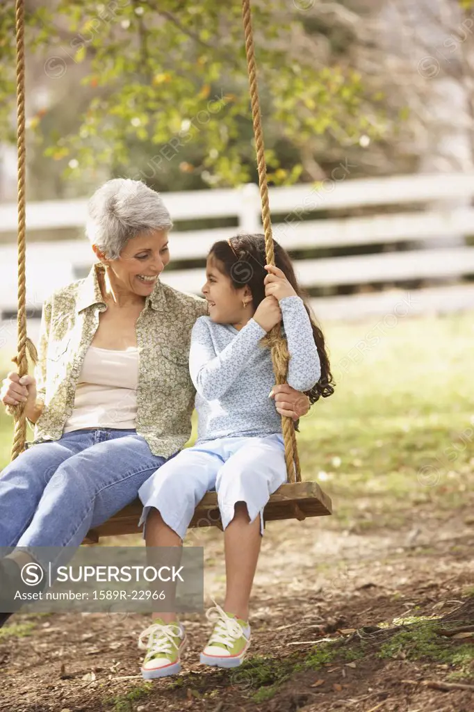 Hispanic grandmother and granddaughter sitting on a swing, Richmond, Virginia, United States