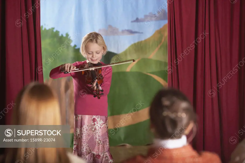 Young girl playing violin at recital