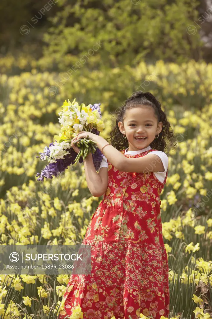 Young Hispanic girl holding picked flowers outdoors