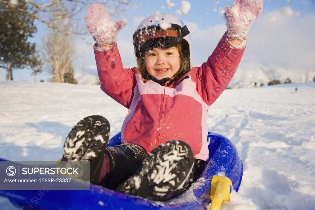 Young girl on sled in the snow, Seattle, Washington, United States