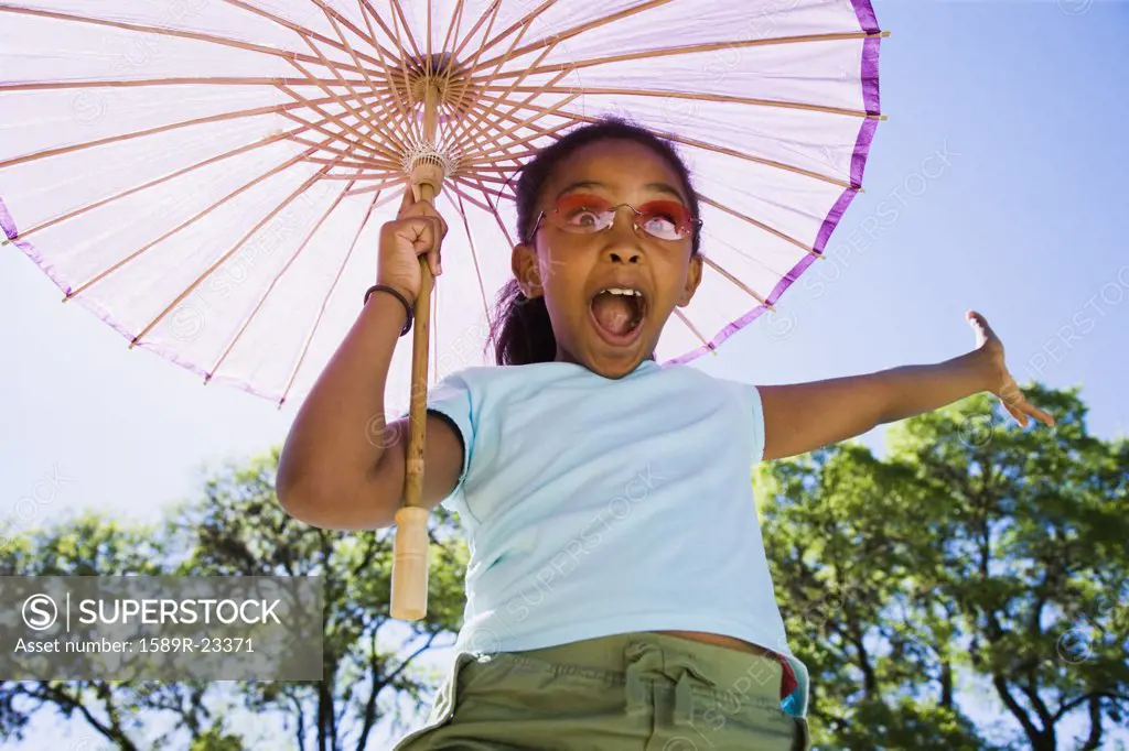 African American girl laughing with parasol outdoors