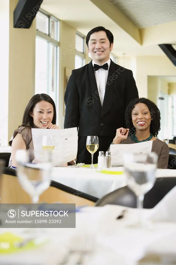 Two women with waiter in restaurant