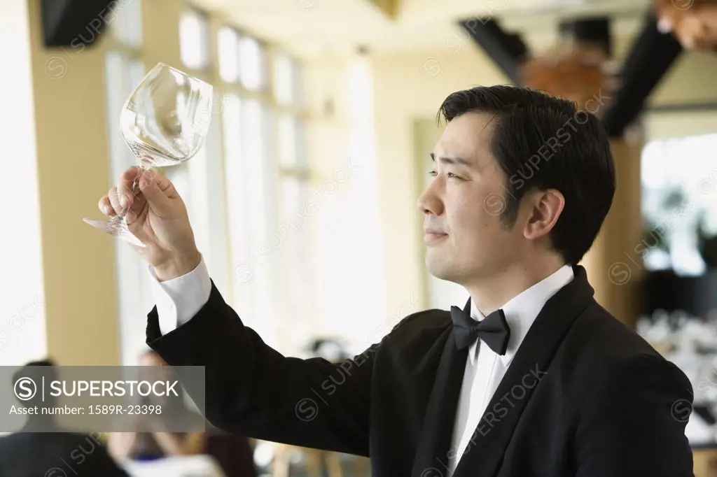Upscale male waiter examining glass