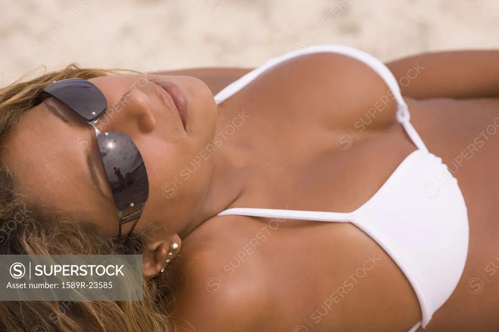 Hispanic woman in bathing suit tanning