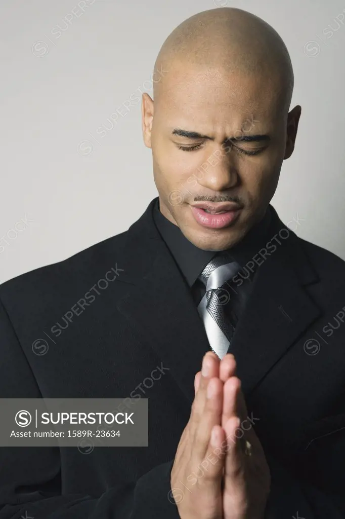 African American man in suit praying