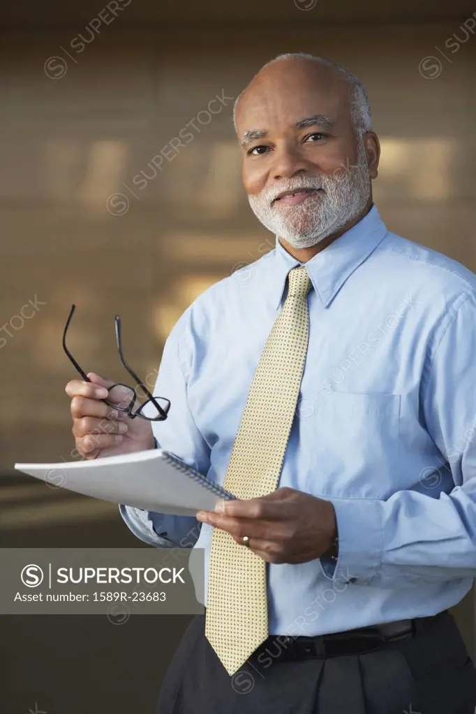 Senior African businessman holding eyeglasses