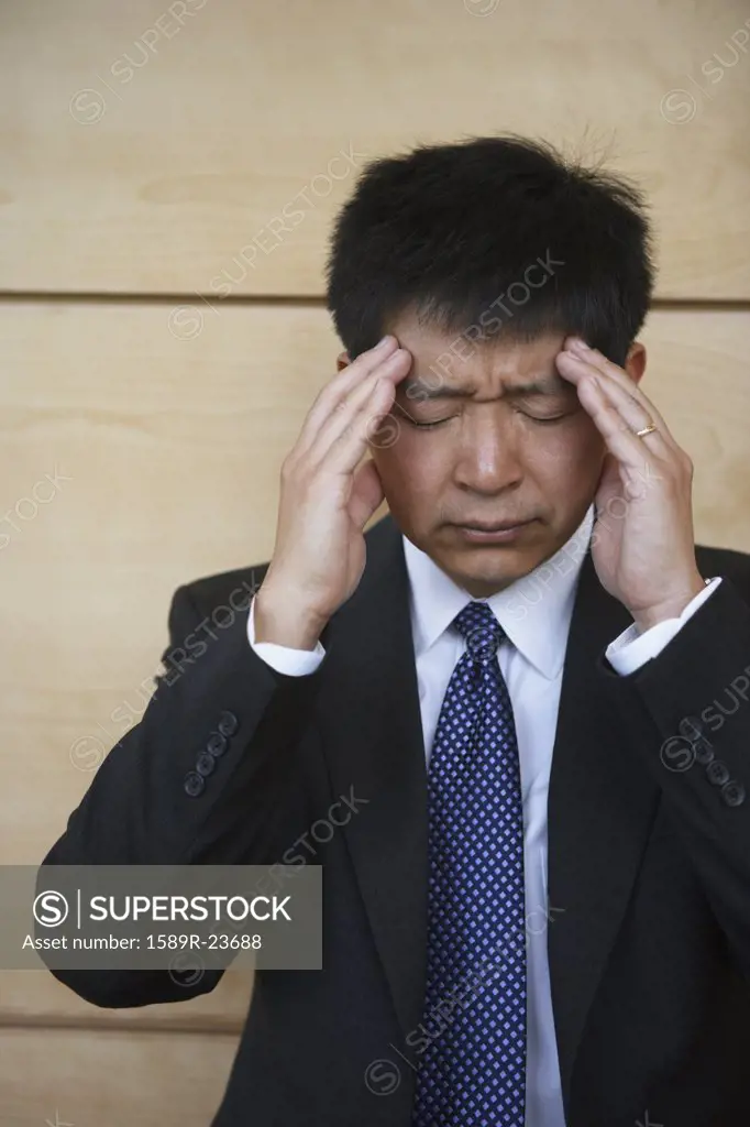 Asian businessman rubbing his temples