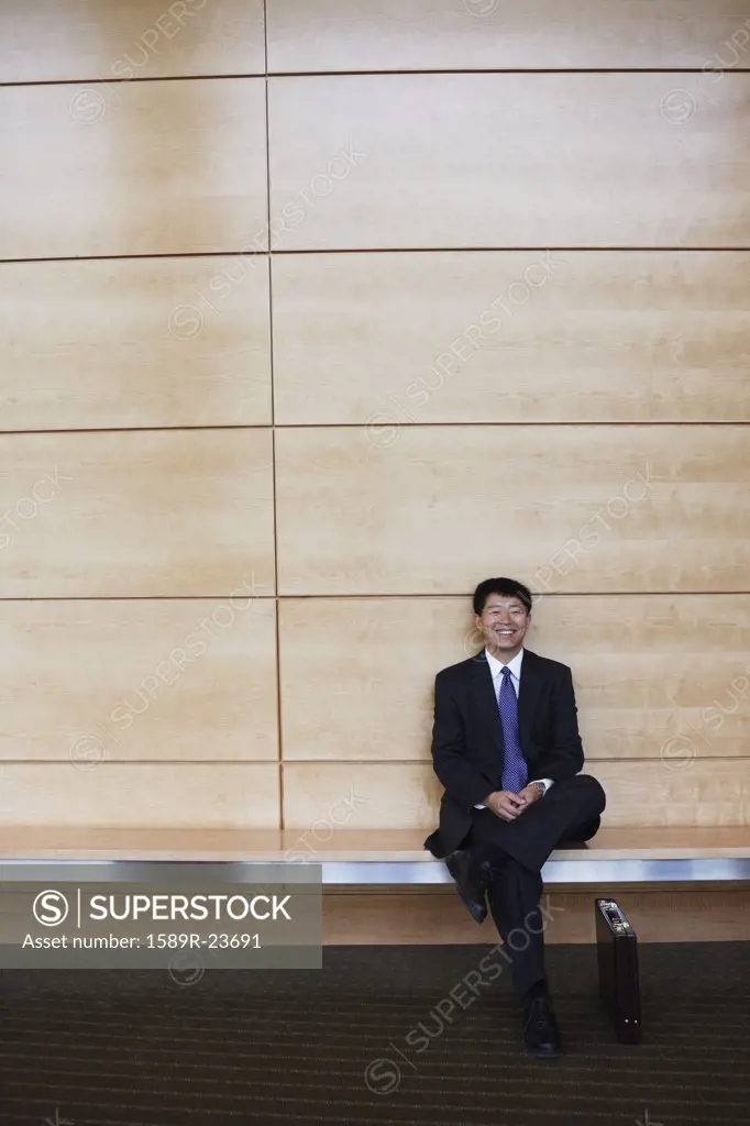 Asian businessman sitting on bench indoors