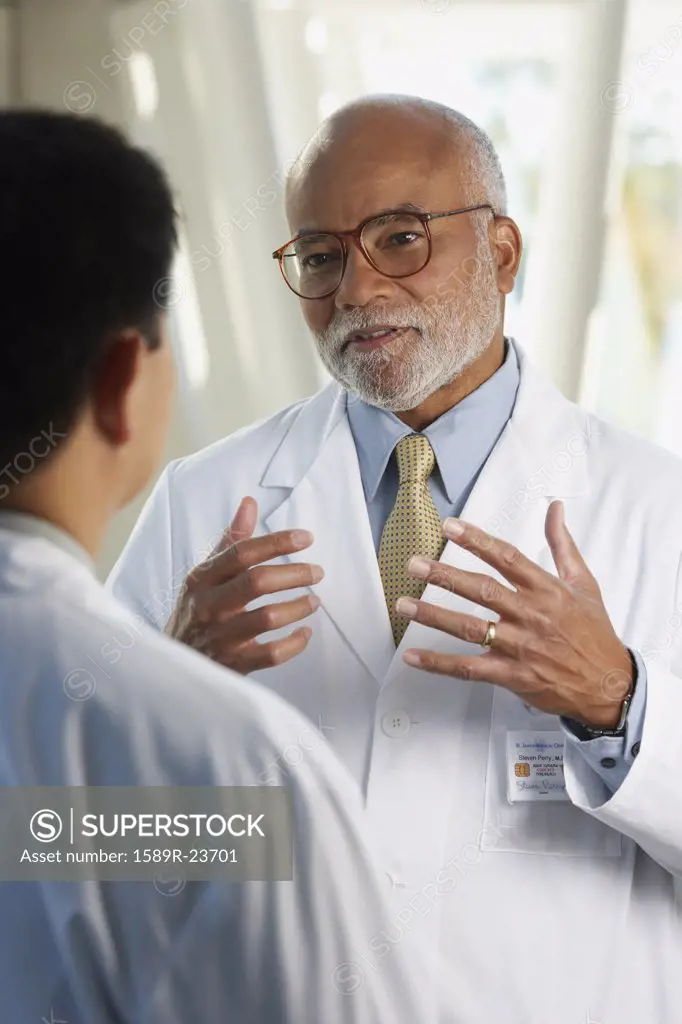 Middle-aged African doctor talking to co-worker