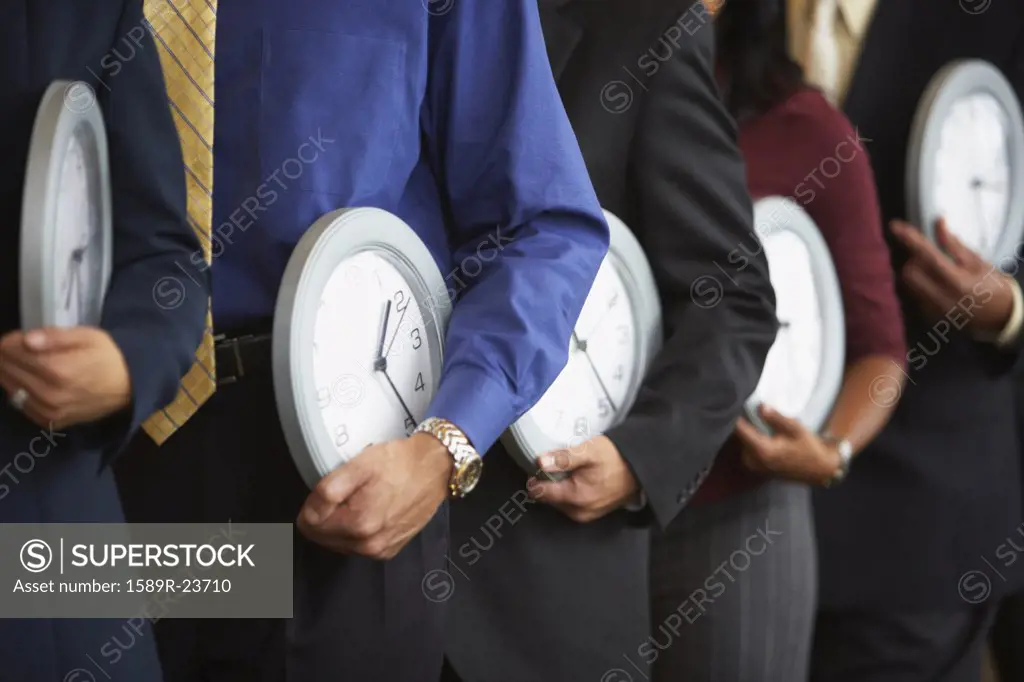 Row of businesspeople holding clocks