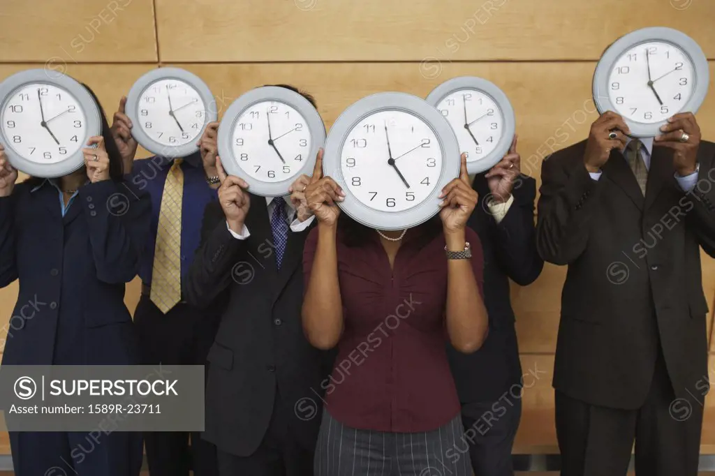 Group of businesspeople holding clocks over their faces