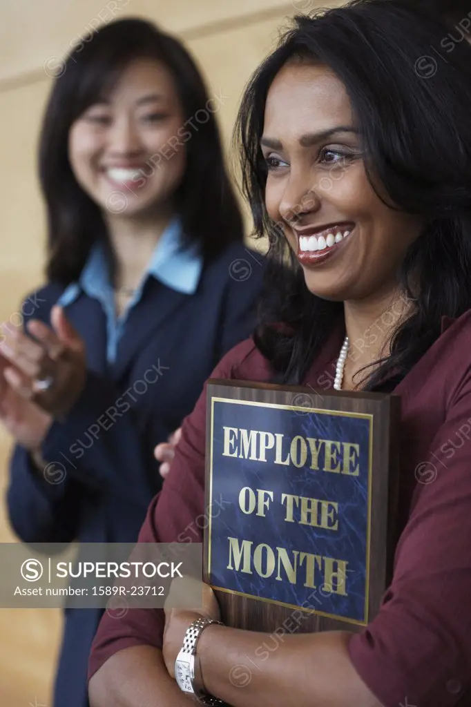 Businesswoman holding Employee of the Month plaque