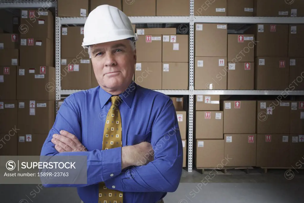 Businessman wearing hard hat in warehouse