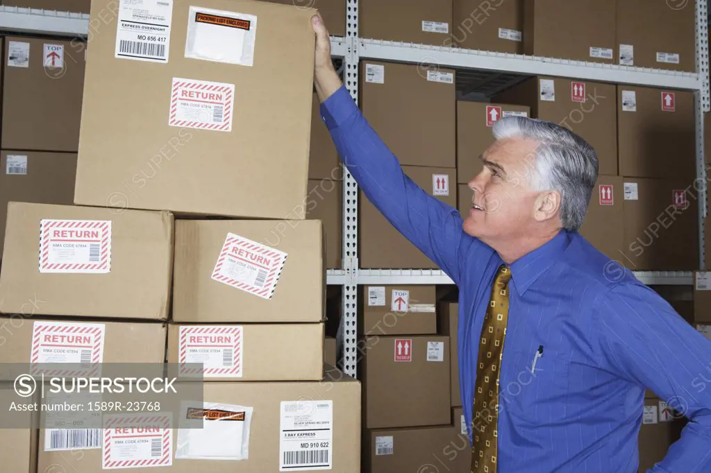 Businessman in warehouse looking at returned packages