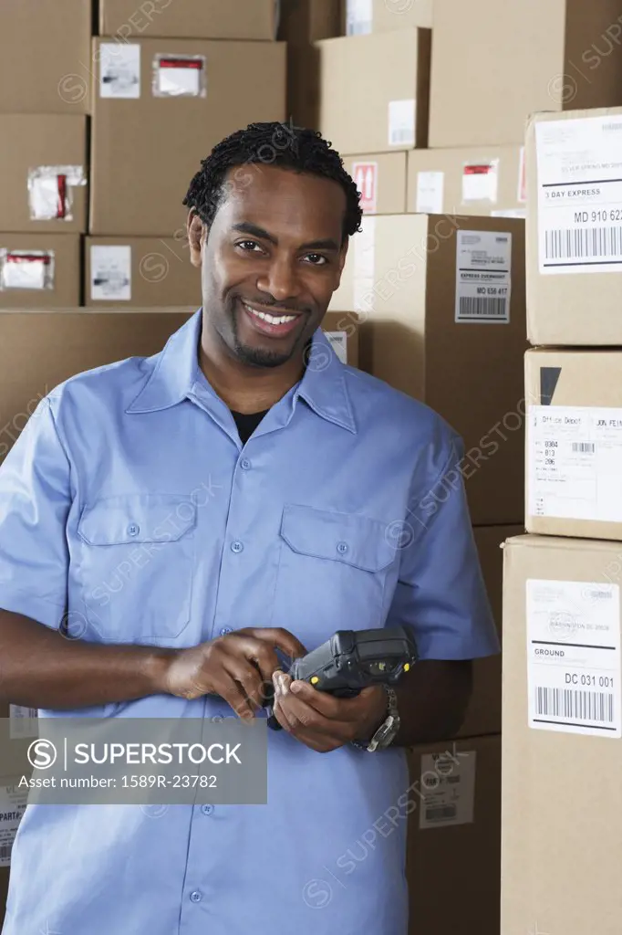Male African warehouse worker scanning packages