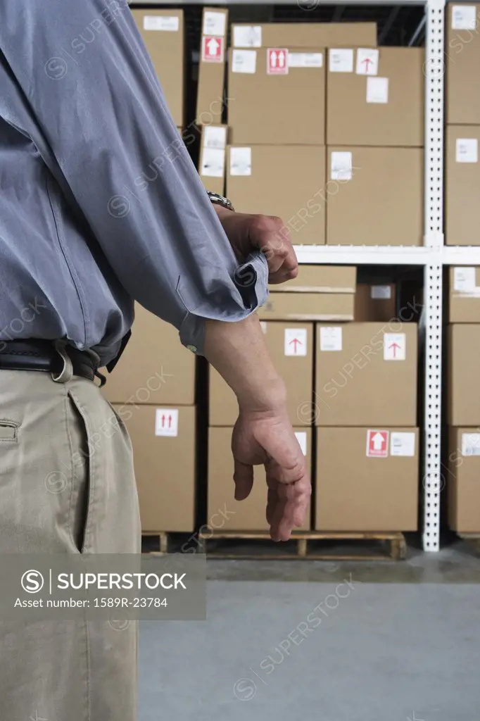 Close up of businessman rolling up his sleeve in warehouse