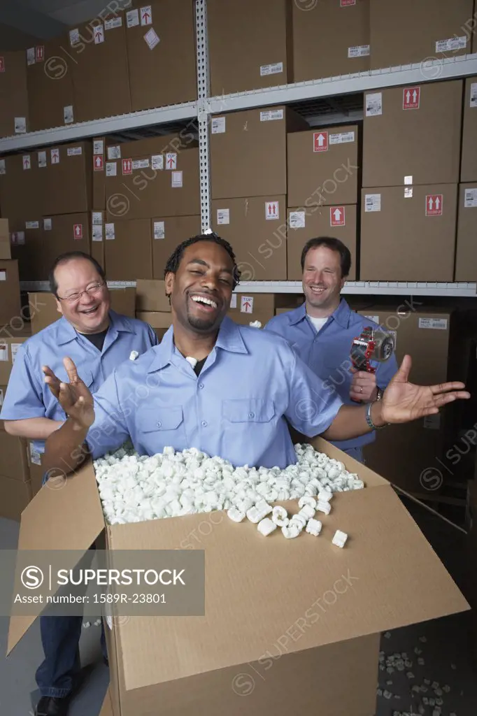 Three male warehouse workers joking around